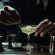 Bartender stirring a classic cocktail in a coupe glass, surrounded by bar tools—capturing the artistry and elegance of traditional mixology.